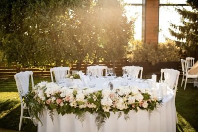 Outdoor wedding reception seating strung with lights in a garden-like park setting