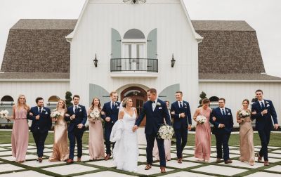 Denton wedding party laughing and celebrating together outside a white barn venue