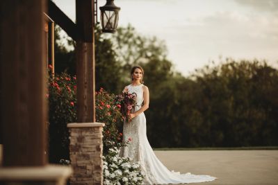 Bride with soft romantic wedding hair and makeup holding a burgundy and blush bouquet