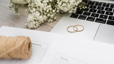 Wedding rings and baby's breath beside a laptop, representing building a wedding website